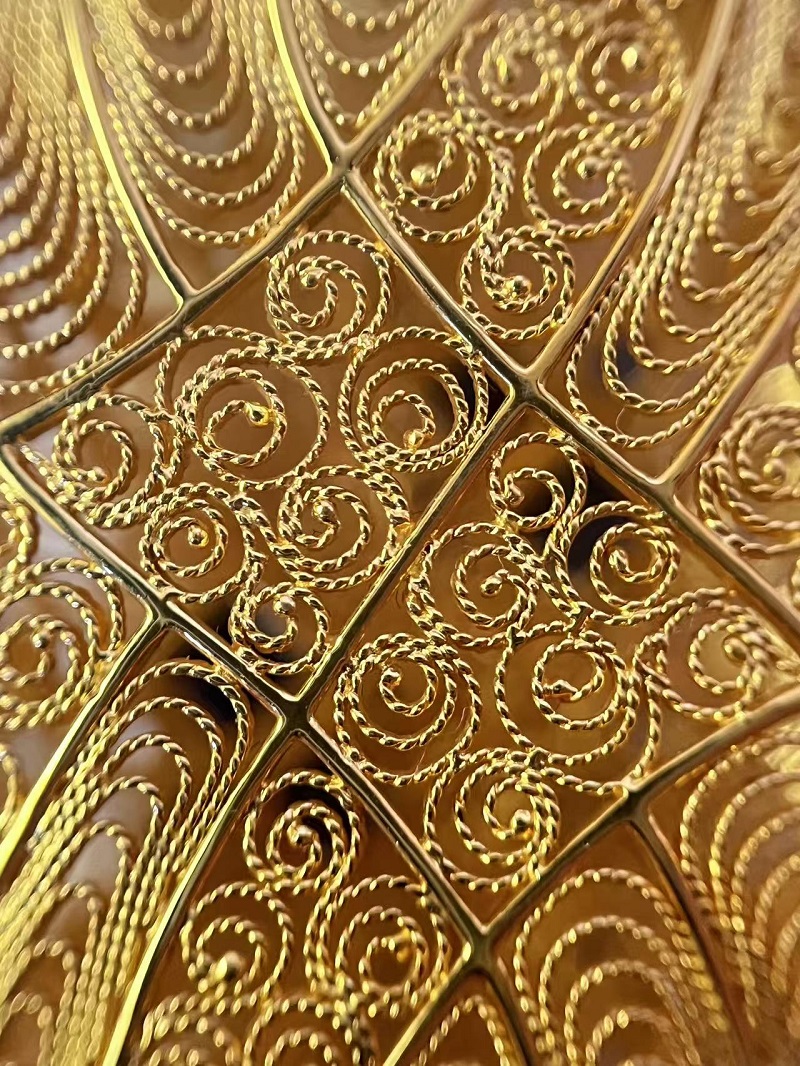 Sonja T. filigree piece featuring openwork gold wire in dragon‑scale pattern framed with a sapphire gemstone